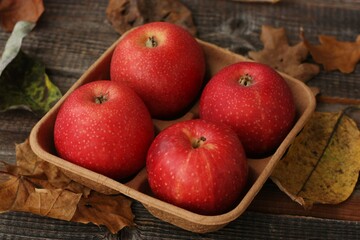 Juicy red apples and autumn leaves on the table