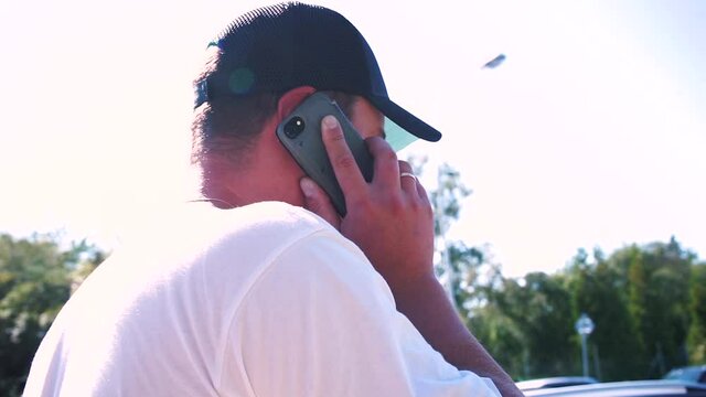 An efficient business telephone system streamlines good communication between organisation and customers. A man in a cap is talking on the phone in motion on a sunny day. 