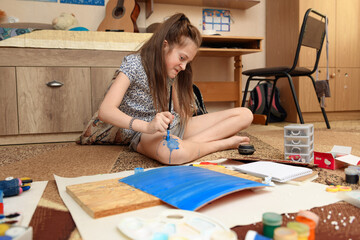 girl draws at home, artistic creation, makes creative artwork from paper, paints and brushes
