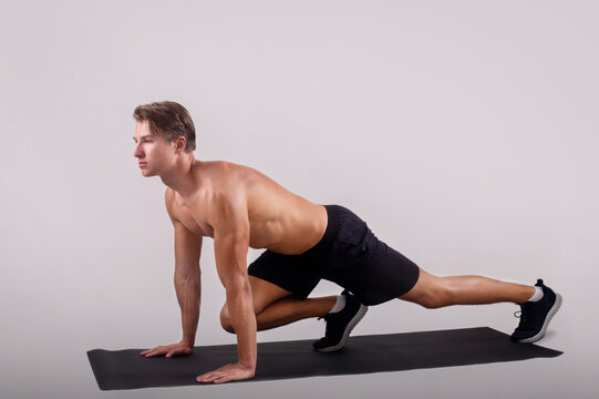 Healthy lifestyle and sports. Strong young man with naked chest exercising on yoga mat over light studio background
