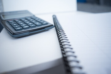 White notebook with calculator on white desk at home office