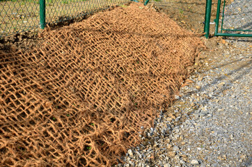 temporary gravel new dirt road. securing the slope against erosion at the door using brown jute...