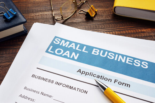 Small Business Loan Application On The Wooden Surface And Documents.