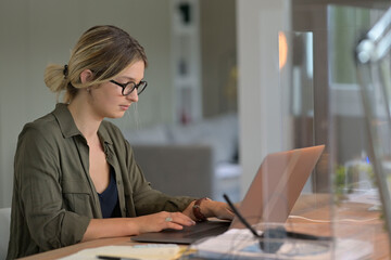 Office worker with eyeglasses working in open space area protected with plexiglas