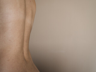 A part of the female back with a bend on a beige background