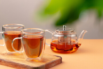 Glass teapot and two glass cups with tea