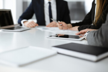Unknown businessmen and woman sitting, working and discussing questions at meeting in modern office, close-up