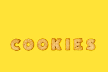 Cookies escrito con letras de galletas sobre un fondo amarillo liso y aislado. Vista superior. Copy space