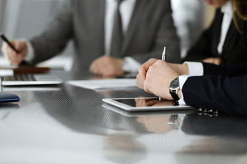 Unknown businessmen and woman sitting, working and discussing questions at meeting in modern office, close-up