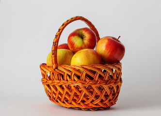Ripe apples in a wicker basket handmade on a white background. Isolated still life