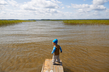 little kid alone on a wooden lake pier
