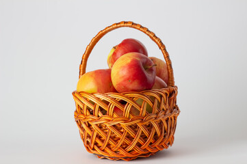 Ripe apples in a wicker basket handmade on a white background. Isolated still life