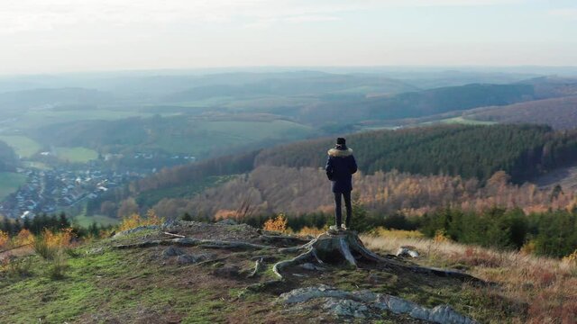 
a man is standing on a hill above a low mountain range filmed in 4k with movement
