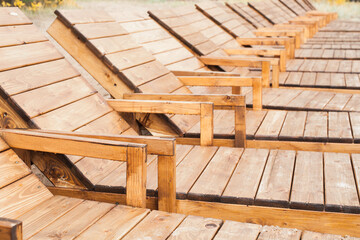 Empty wooden sun lounges stand in a row