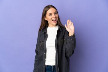 Young Lithuanian woman isolated on purple background saluting with hand with happy expression