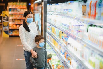 Young woman and her kid wearing protective face masks shop a food at a supermarket during the coronavirus epidemic or flu outbreak