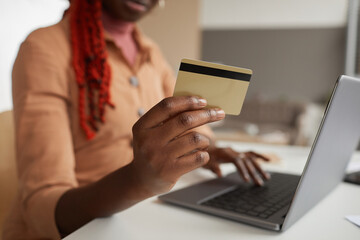 Close up of unrecognizable African-American woman holding credit card while shopping online from...