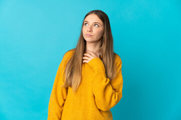 Fototapeta premium Young Lithuanian woman isolated on blue background looking up while smiling