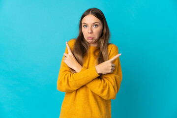 Young Lithuanian woman isolated on blue background pointing to the laterals having doubts