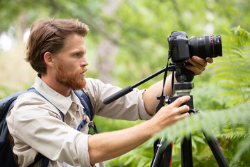 photographer looking at screen of  dslr camera on tripod