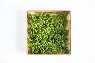 Green pasta in a cardboard box on a white background. Top view. Copy, empty space for text