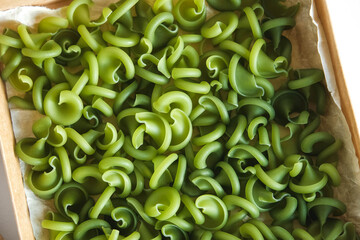 Green pasta in a cardboard box on a white background. Top view. Copy, empty space for text