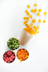 Multicolored pasta in a disposable kraft paper cups on a white background. Top view. Copy, empty space for text