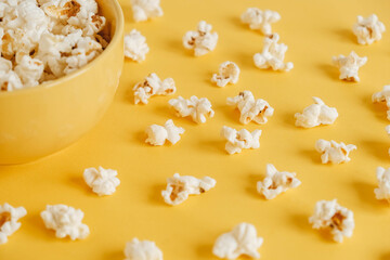 Popcorn in a yellow bowl on a yellow background. Top view. Copy, empty space for text