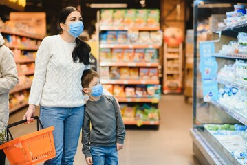 Young woman and her little son wearing protective face mask shop a food at a supermarket during the coronavirus epidemic or flu outbreak