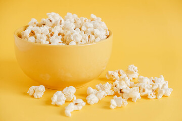 Popcorn in a yellow bowl on a yellow background. Copy, empty space for text