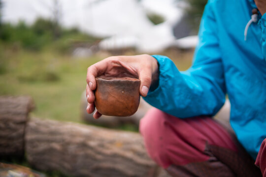Drinking Chinese tea Pu Erh outdoor Near the Campfire Oven in Ecovillage. Clay tea pot, cup and pot on the little wooden table