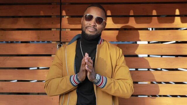 Stylish African American man puts on sunglasses