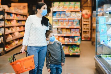 Authentic shot of mother and son wearing medical masks to protect themselves from disease making shopping for groceries together in supermarket.