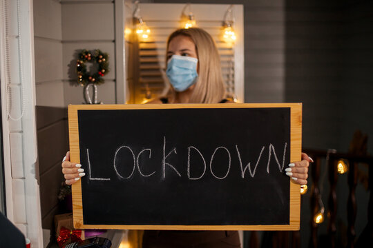 Woman waiter in protective mask taking in hands nameplate Lockdown. She depressed and  worried about losing her job