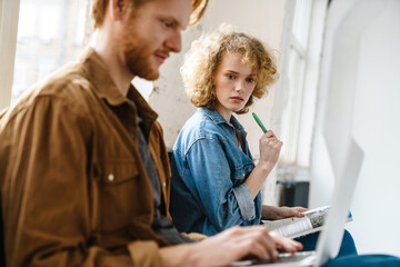 Young beautiful redhead couple making down notes and working with laptop