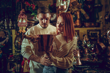 Obraz premium Golden. Smiling family, caucasian couple looking for home decoration and holiday's gifts in household store. Stylish and retro things for greetings or design. Interior renovation, celebrating time.