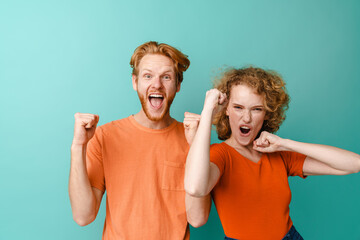 Young excited redhead couple screaming and making winner gesture