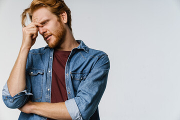 Unhappy ginger guy with headache posing at camera