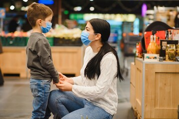Young woman and her little son wearing protective face mask shop a food at a supermarket during the coronavirus epidemic or flu outbreak