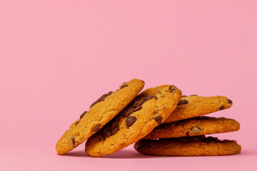 Stacked chocolate chip cookies against pink background