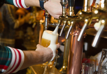 Beer is pouring from the tap into the glass. At the beer bar.
