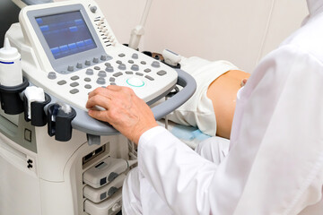 The doctor is sitting at the ultrasound machine. Diagnostic apparatus