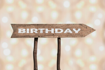 Birthday wooden arrow road sign against bokeh background.