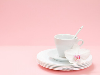 White cup and plates on a pink background.