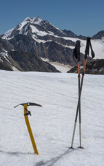 ice axe and hiking poles in fresh snow in the austrian Alps with majestic mountain in the background