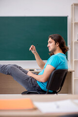 Young male student in front of green board