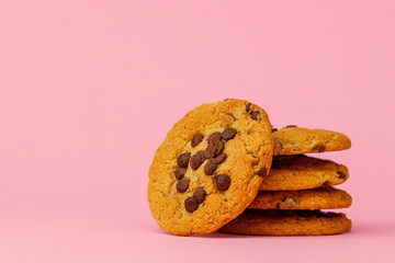 Stacked chocolate chip cookies against pink background