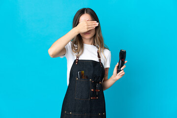 Young Romanian hairdresser woman isolated on blue background covering eyes by hands. Do not want to see something