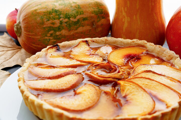 Apple tart pie on table with pumpkin and dry leaves