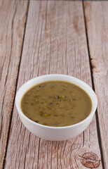Mung beans porridge (bubur kacang hijau) is a Malaysian traditional dish usually eat as starter or desert. Made from mung beans, coconut milk & palm sugar. Isolated over wooden background.